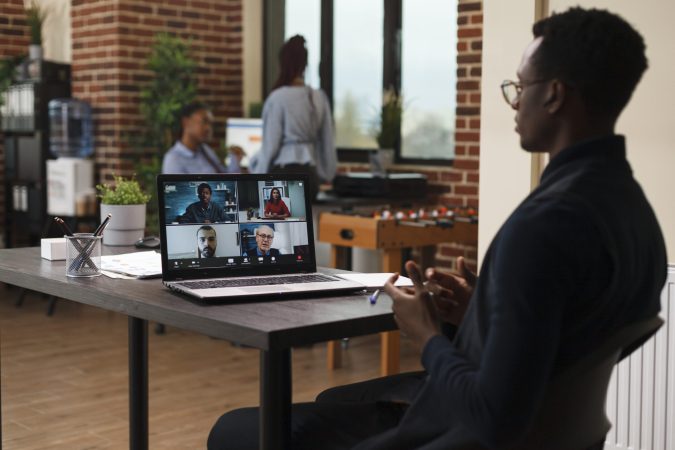 Marketing agency office worker talking with coworkers on digital video meeting call while in office. Company employee on remote videocall conference with clients talking about project revenues